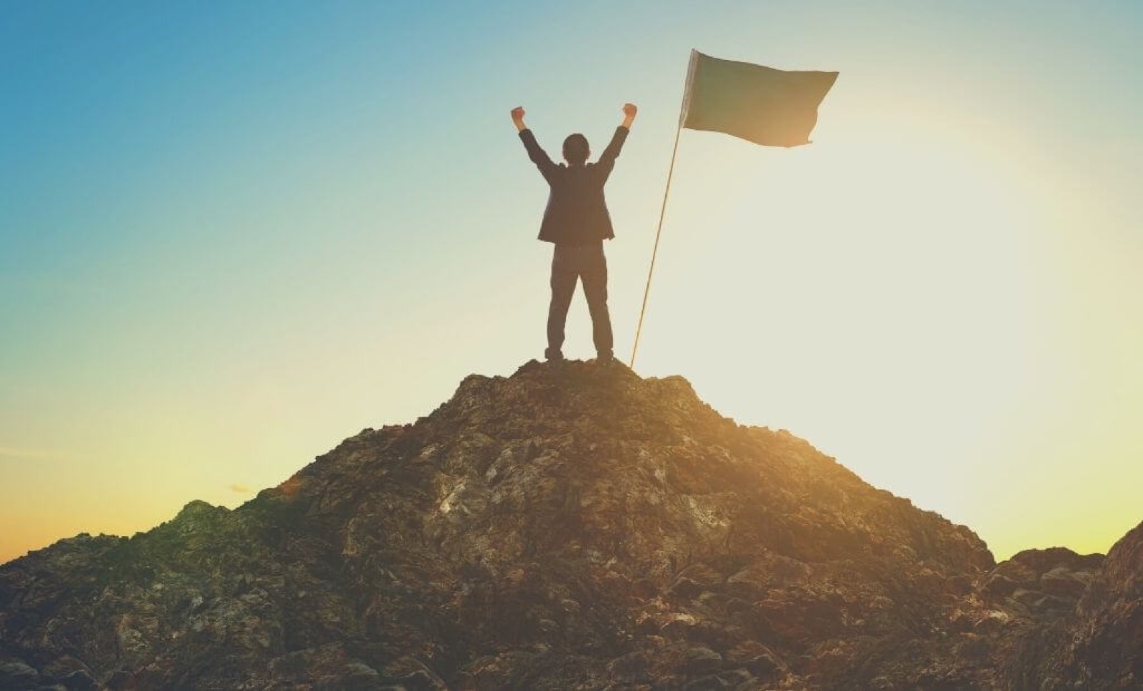 Businessperson planting a flag on a summit, progress achieved